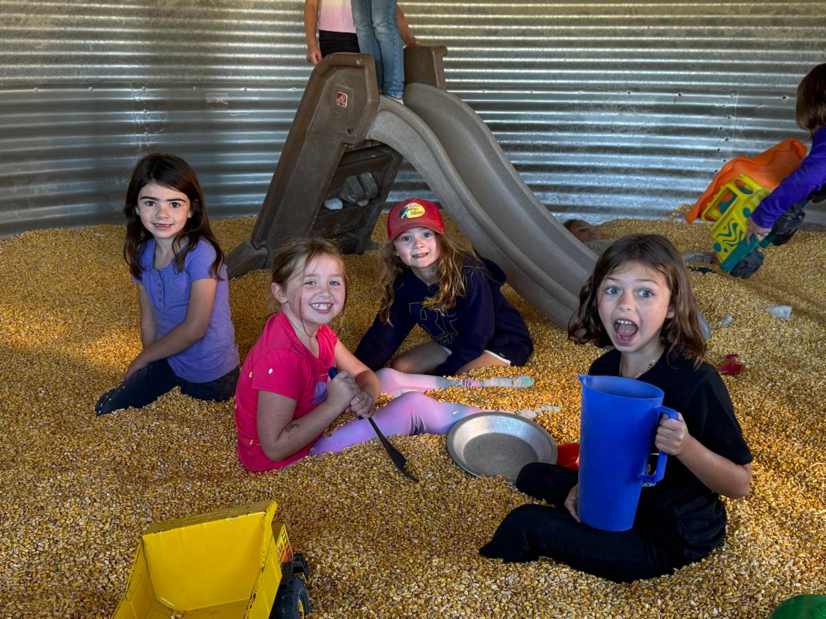 girls with buckets in a corn bin