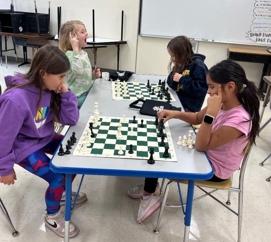 four elementary girls play chess
