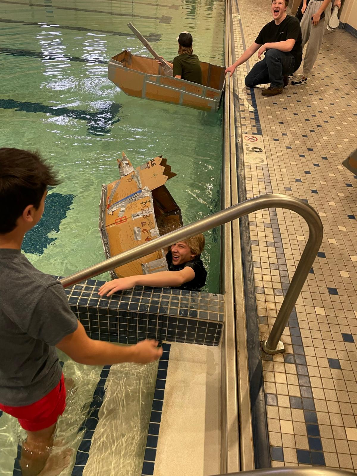 student in water with cardboard boat 