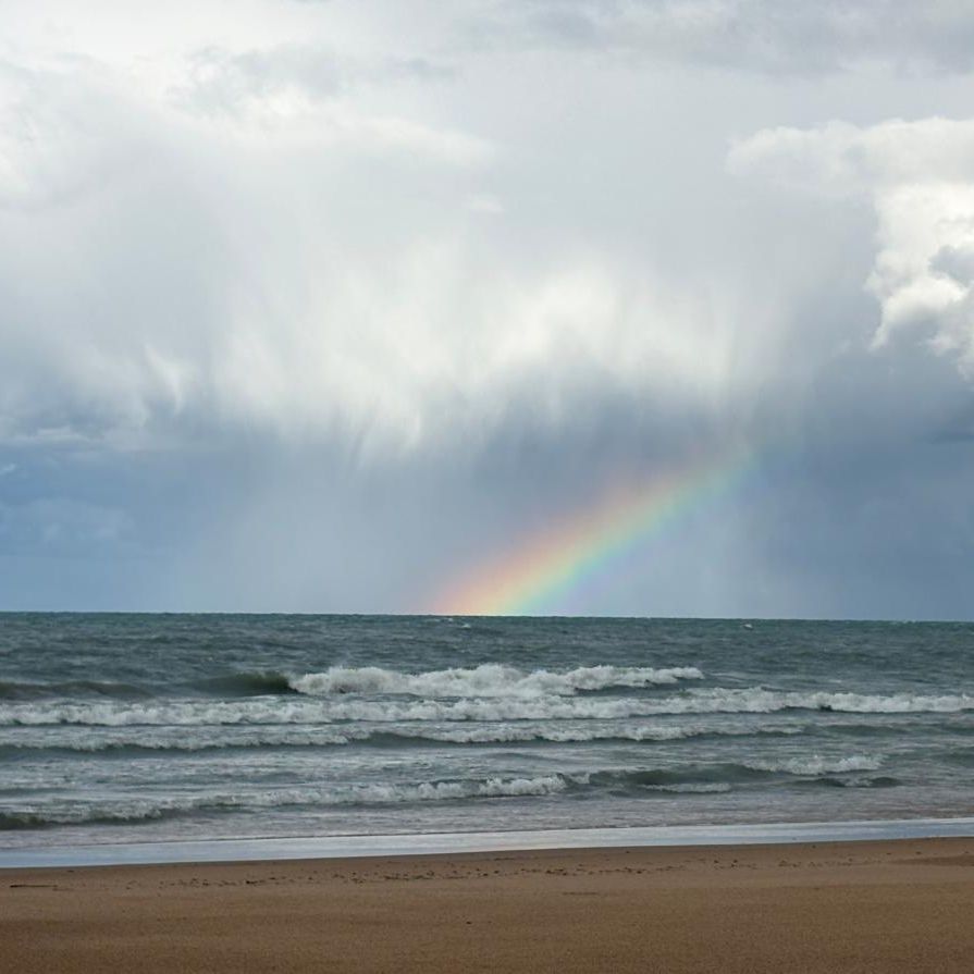Rainbow emerges from a storm cloud over the Lake Michigan shoreline.