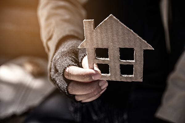 Hand holding a cardboard cutout of a house