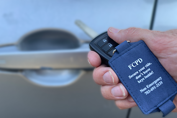 A hand holding a key chain that says don't leave your keys in the car