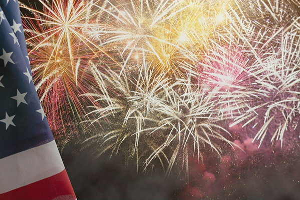 A fireworks diplay with an American flag in the foreground