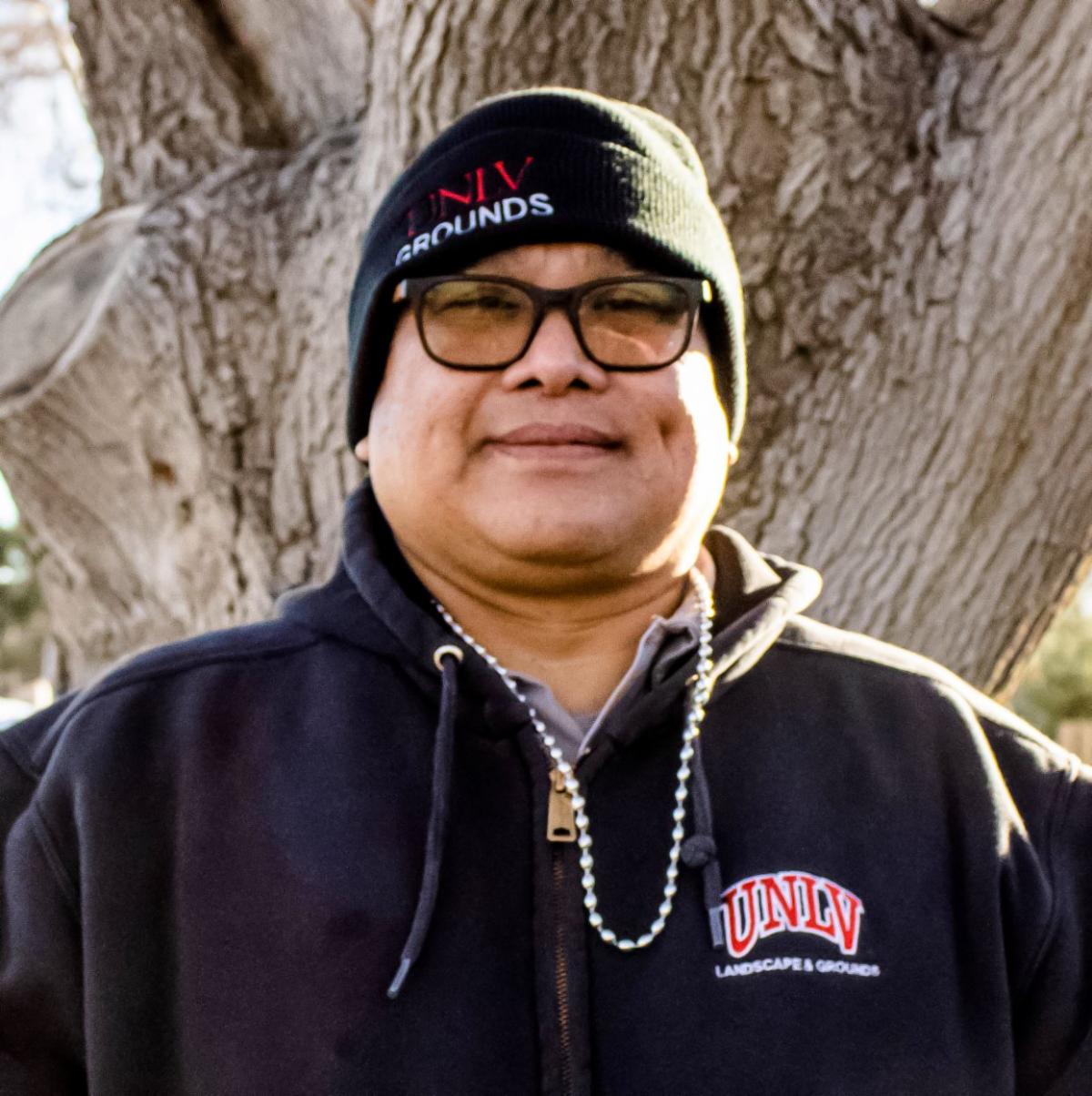 Photo of Jemil standing on campus near a tree.