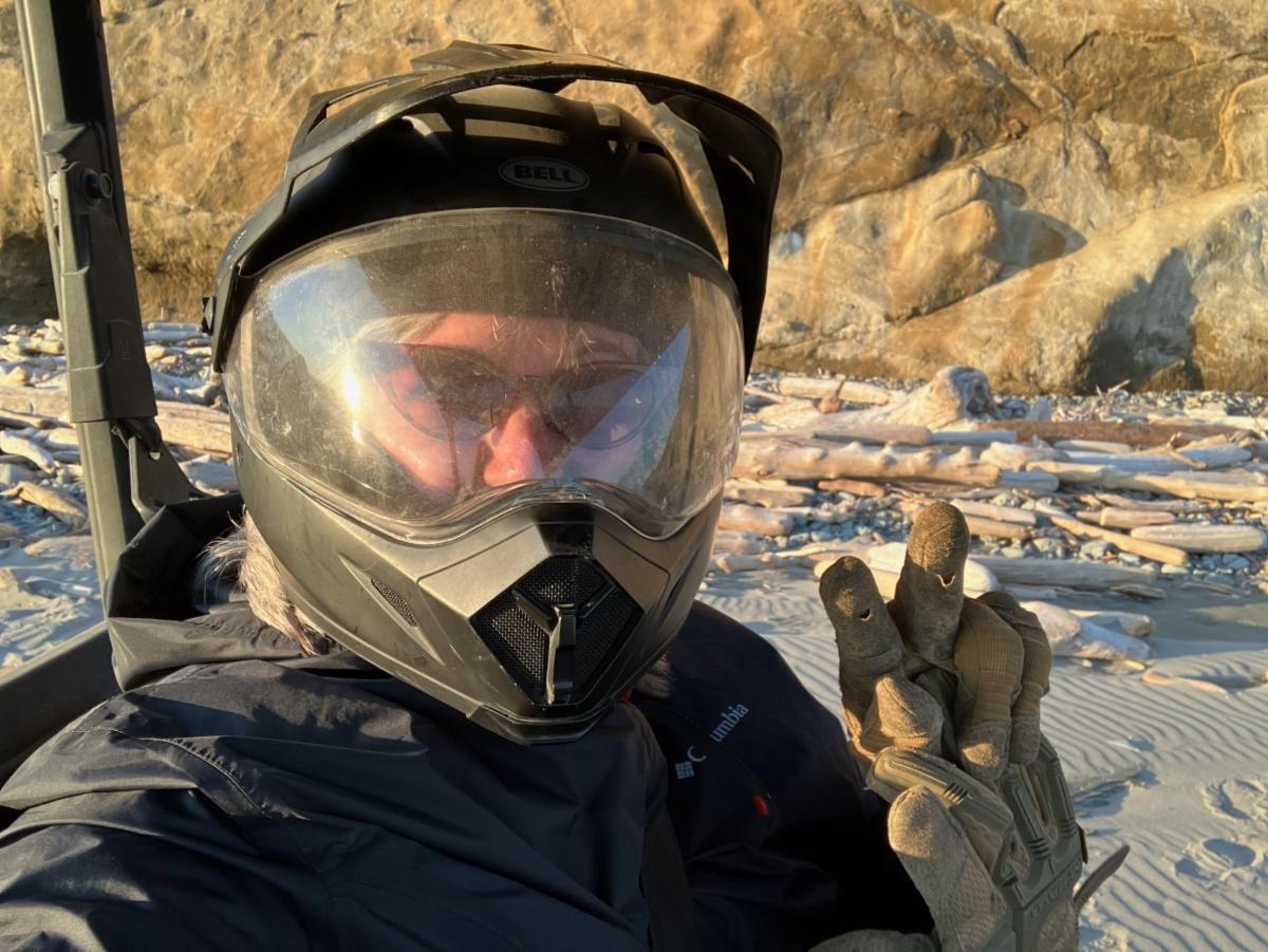 Heather Stinnett wearing a helmet with face shield and other protective gear holding up the peace sign with two fingers