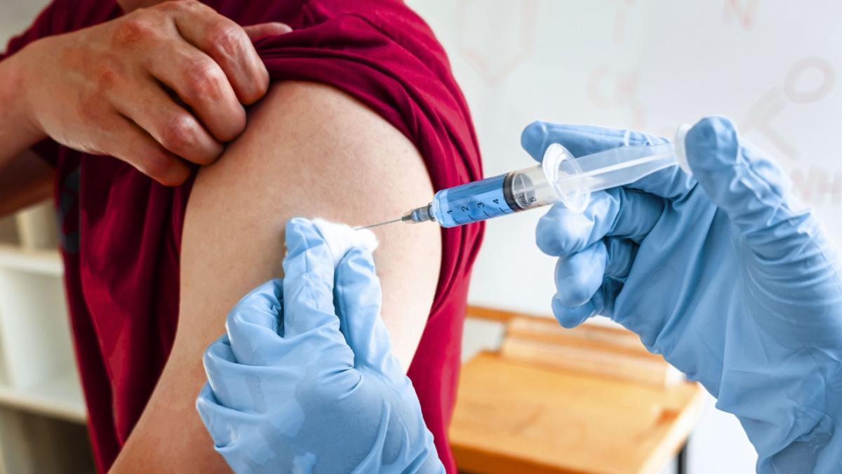 Person in a red shirt receiving a vaccine