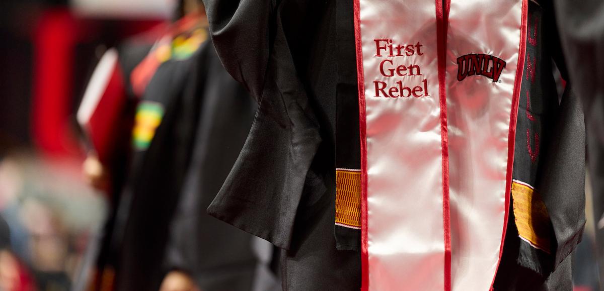 Graduate with a sash reading "First Gen Rebel"