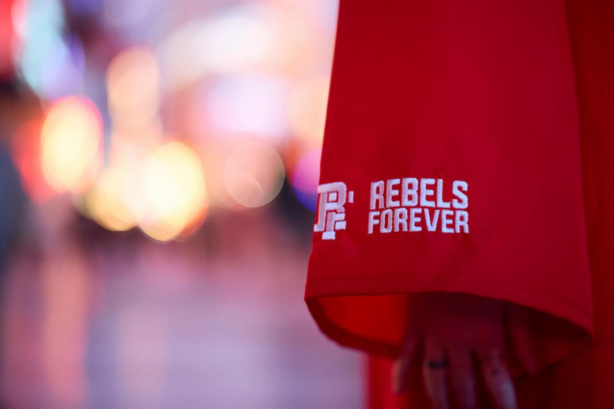 Sleeve of graduation gown with embroidered text: Rebels Forever