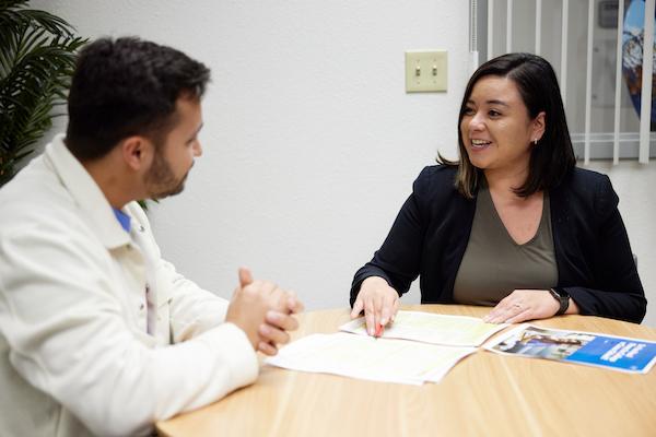 Professionally dressed woman and man talking over some papers at a table.