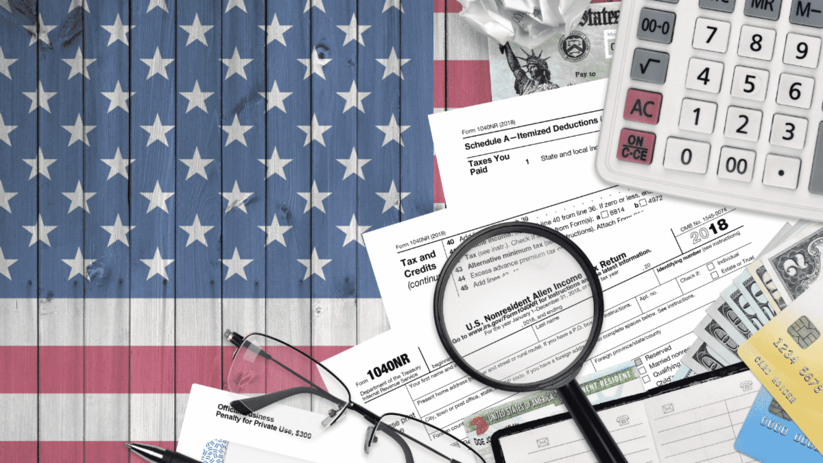 Image of 1040NR tax documents for nonresident aliens with United States of America flag background