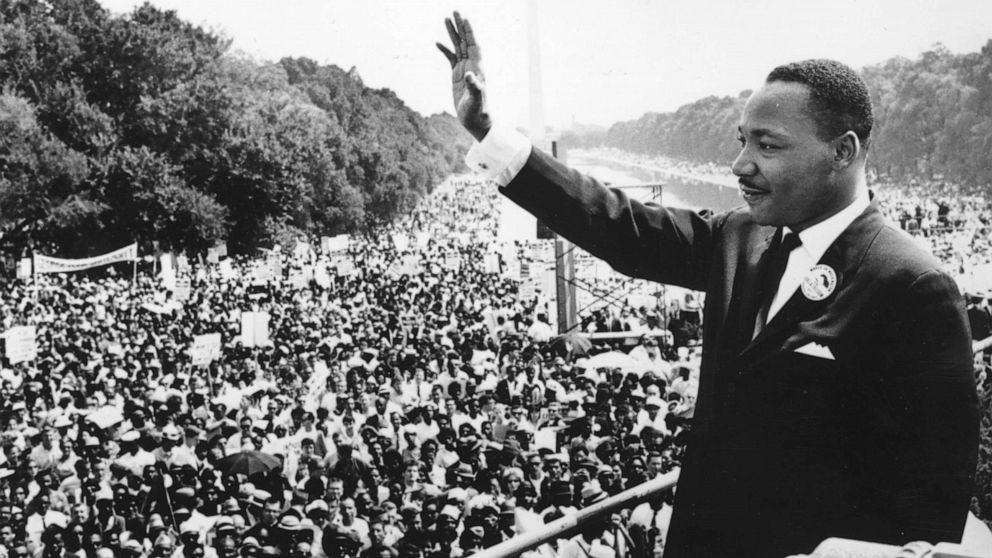 Black and white picture of MLK waving to a crowd of people