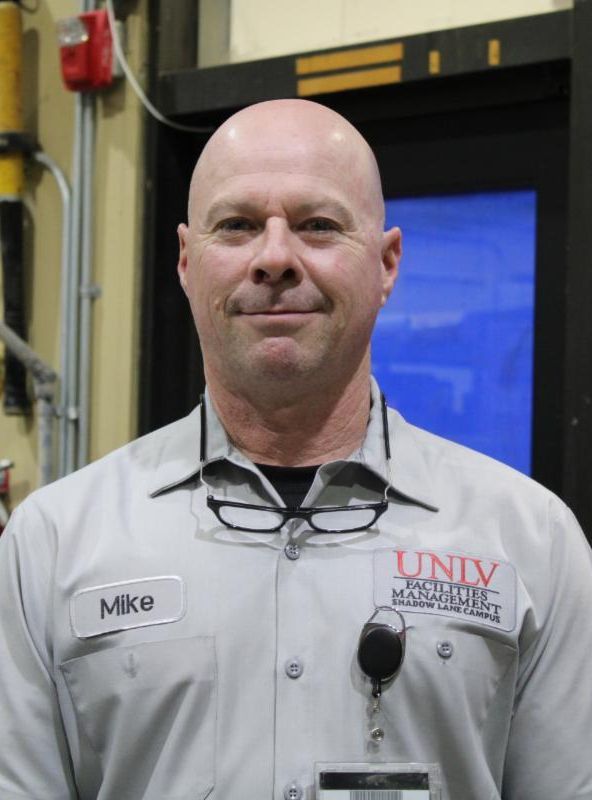White bald man in a gray uniform shirt