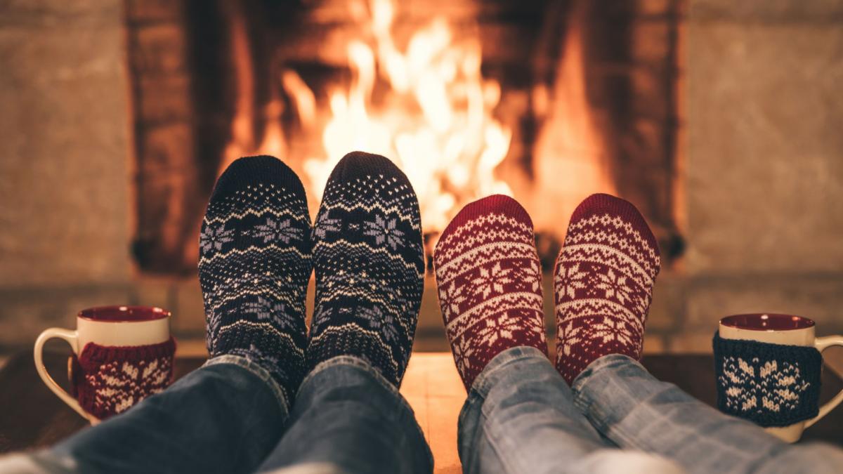 People wearing fuzzy socks relaxing in front of a fire