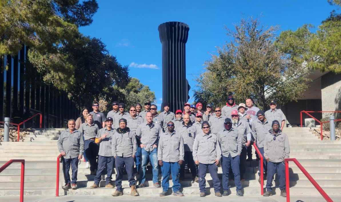 A group photo of the Landscape, Grounds, and Arboretum Services team standing on stairs near the Performing Arts Building. 