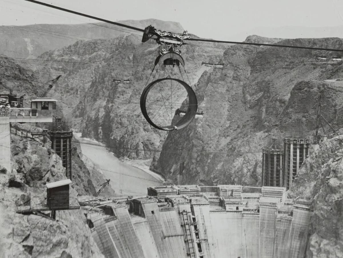 Large pipe with person inside being transported over Hoover Dam in 1934
