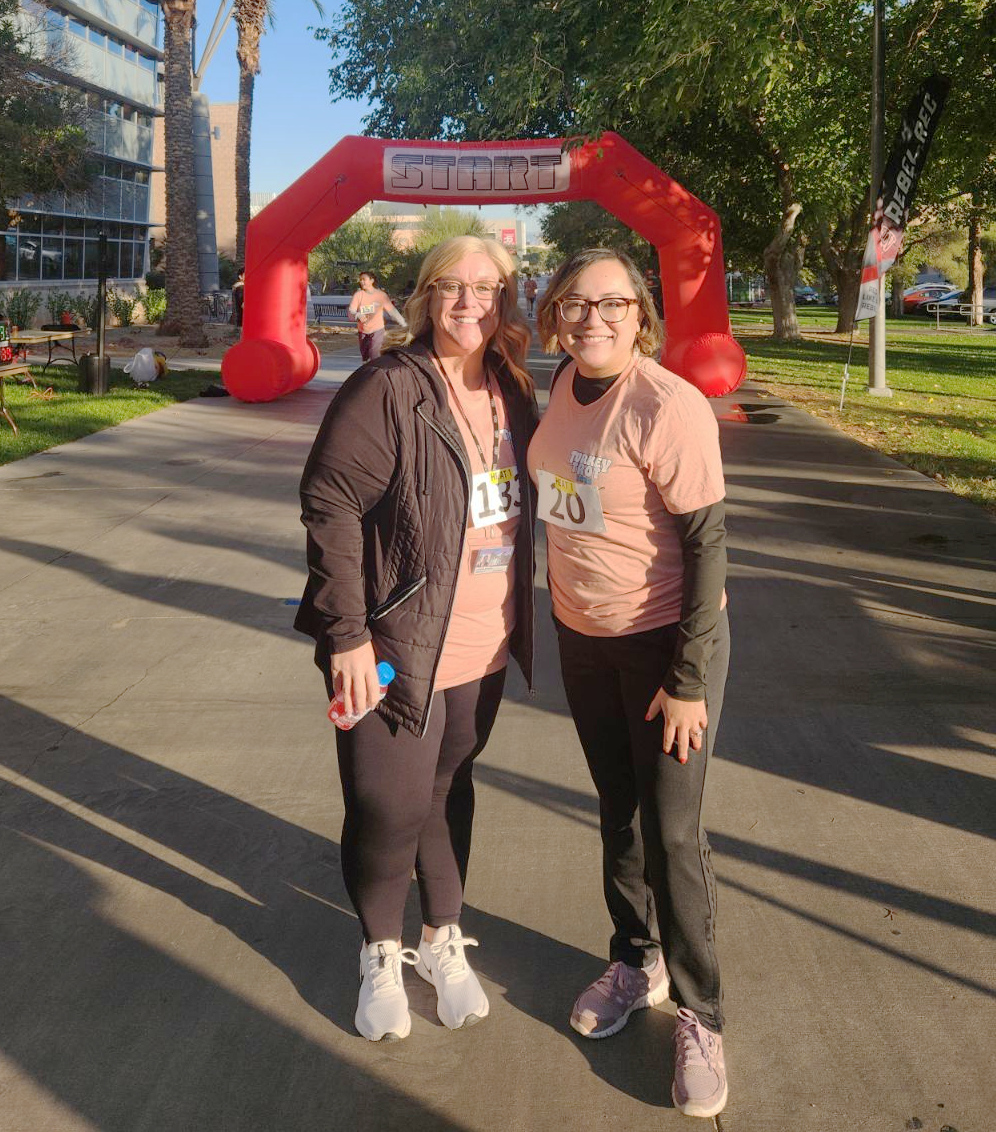 Two Business Affairs Employees pose at the Turkey Trot starting line