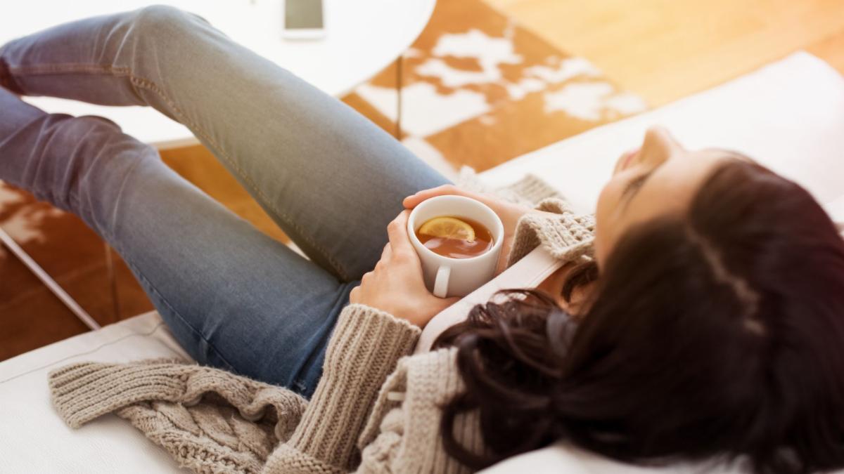 Woman relaxes on couch with cup of tea
