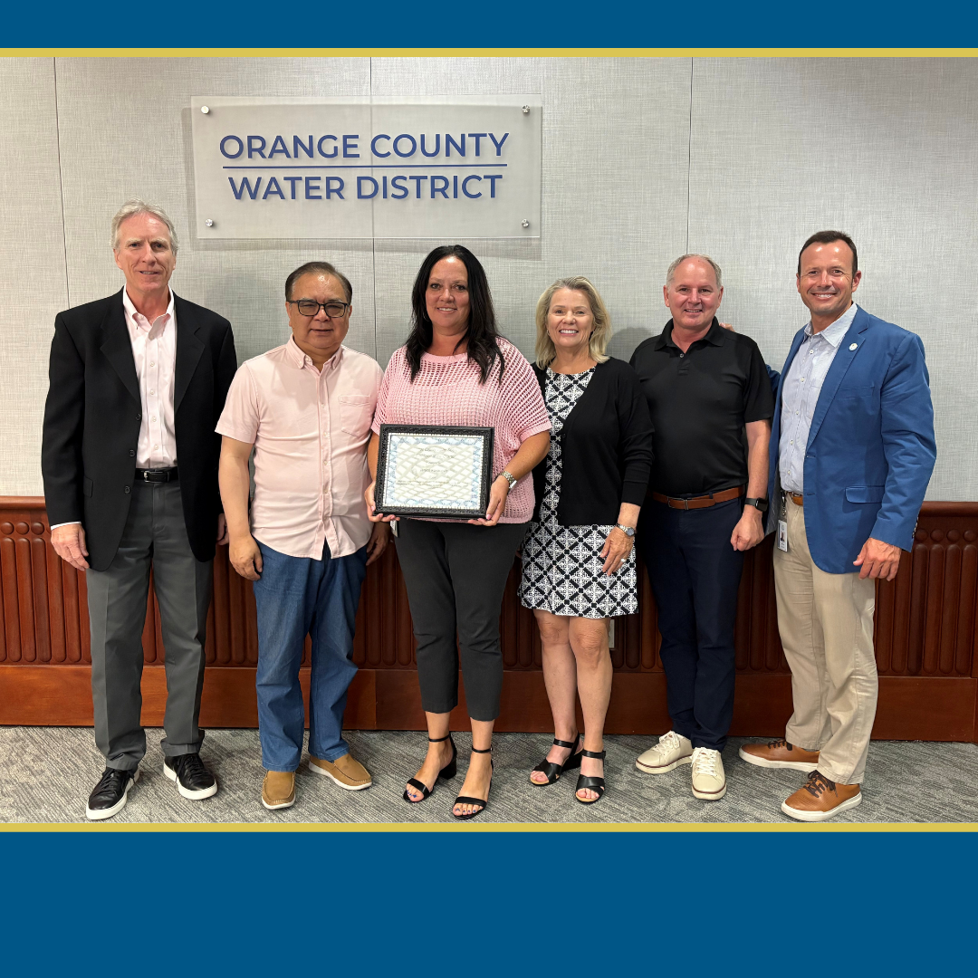 Picture of Janice Kovacevic receiving her award at an OCWD Board Meeting, pictured with OCWD General Manager and Board Members