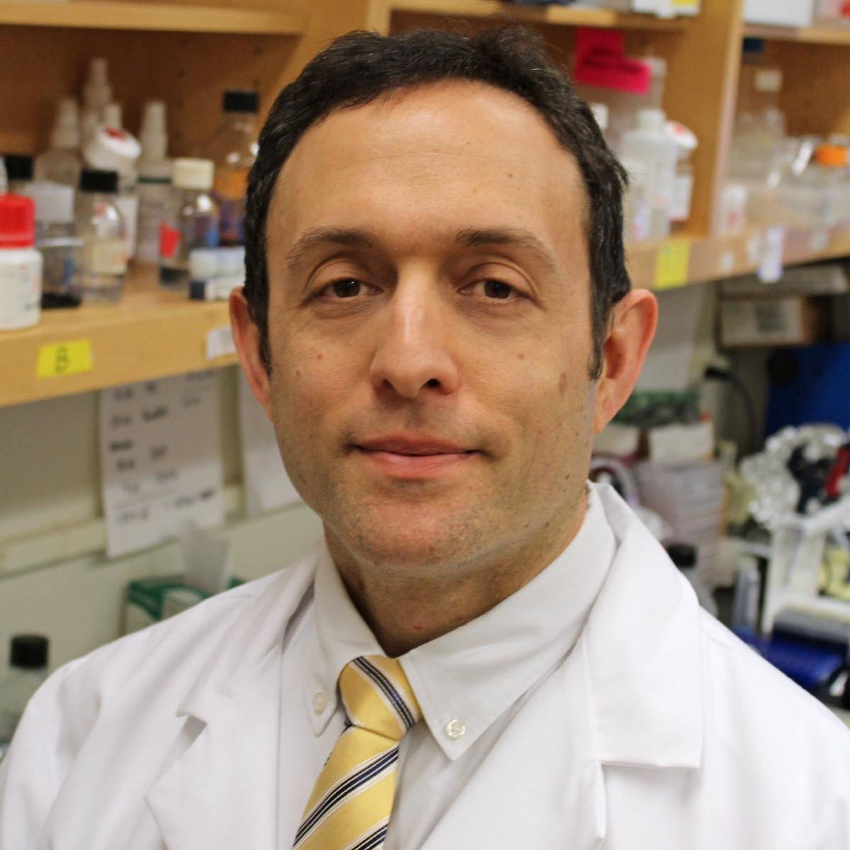Headshot of Peter Cole in lab coat and yellow tie inside research lab