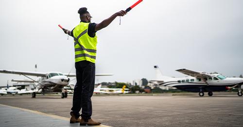 Man signaling the pilot with marshalling wands at airport