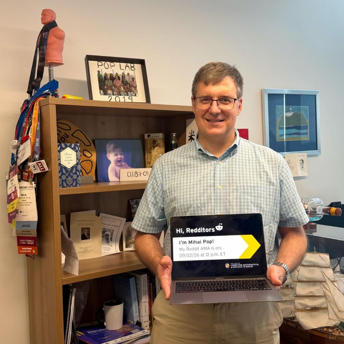 Mihai Pop standing in his office holding a laptop displaying a Reddit AMA announcement.