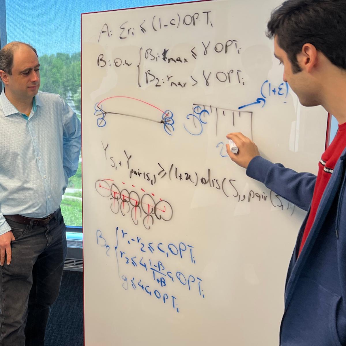 Mohammad Hajiaghayi and a student write equations on a whiteboard