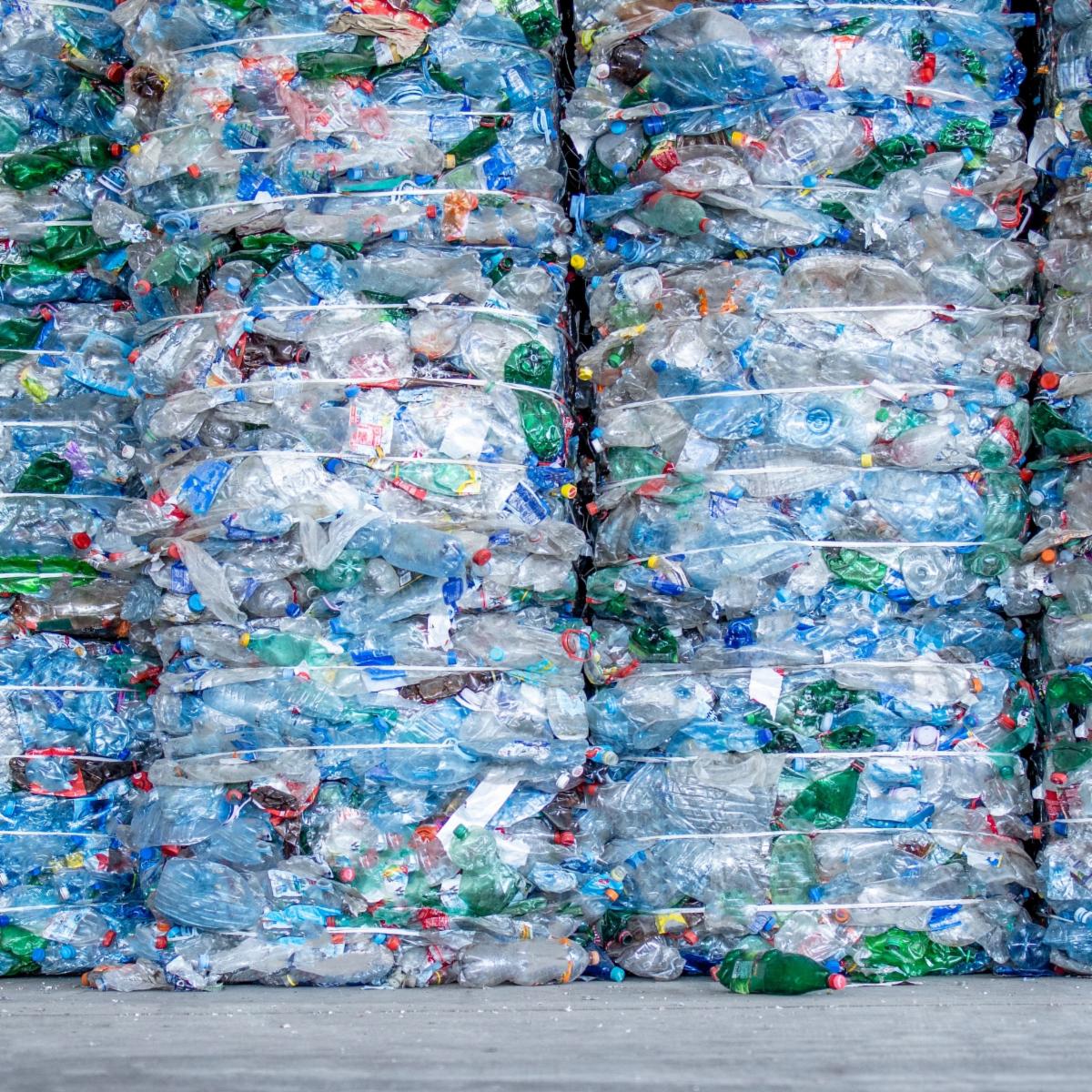 Bundled plastic waste is piled together against a wall.