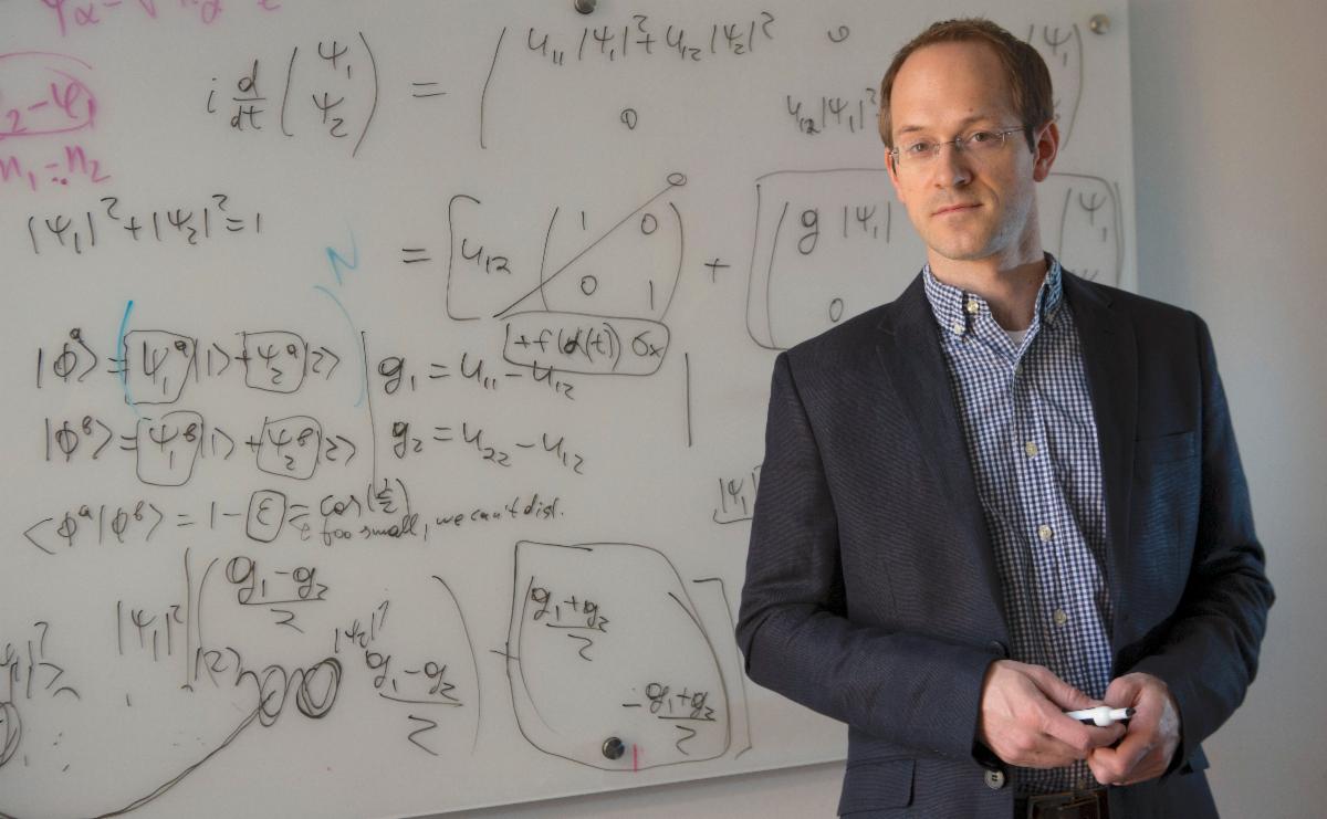 Andrew standing in front of white board full of equations