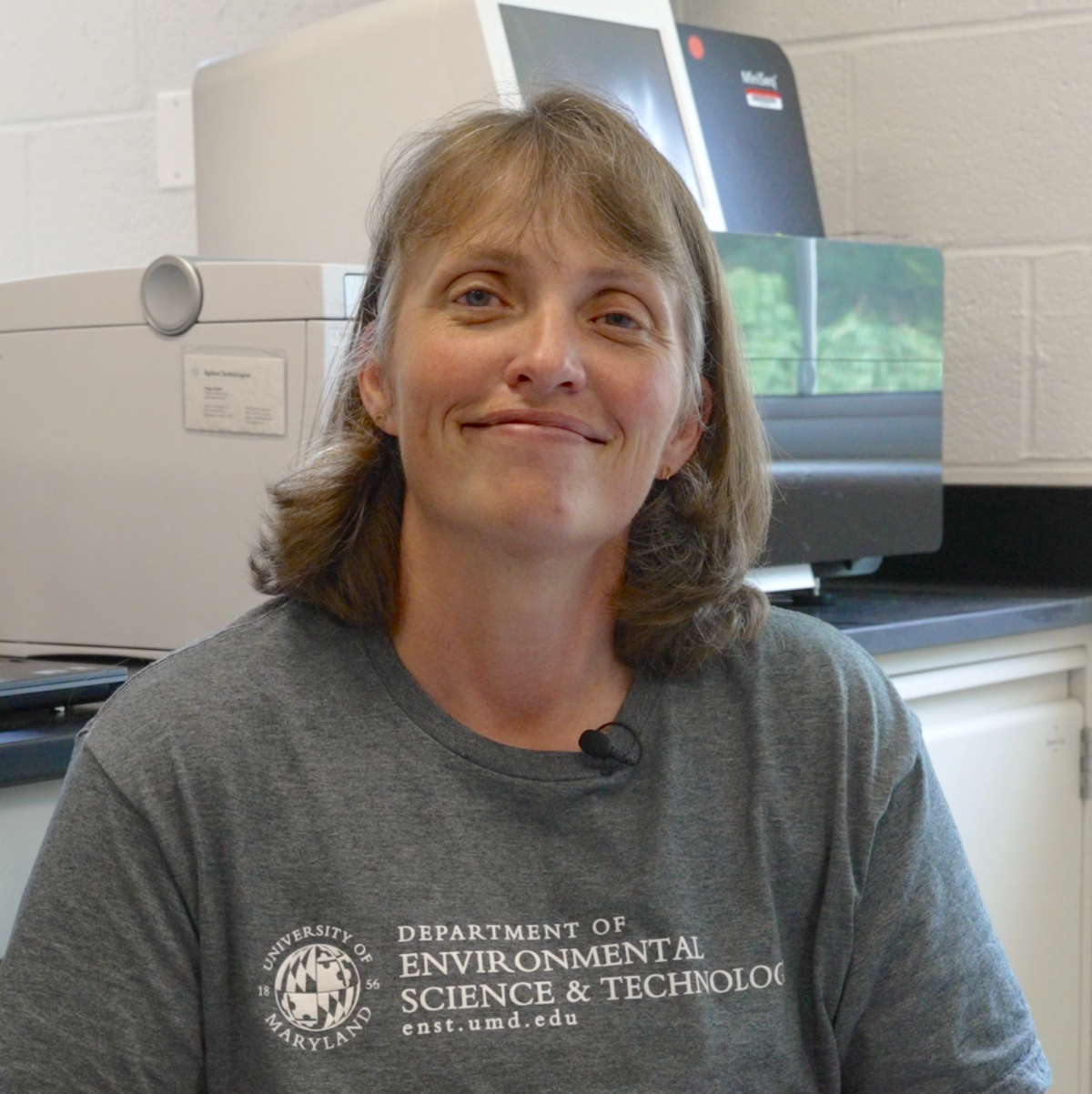 Stephanie wearing gray department t-shirt smiling in lab