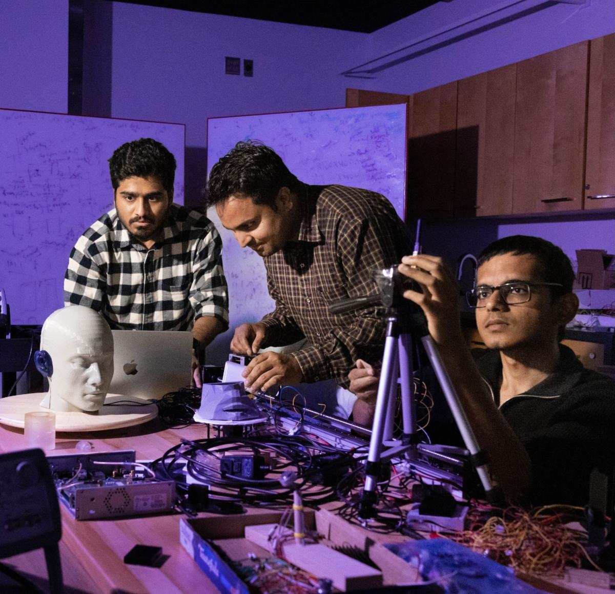 Three graduate students work in Nirupam Roy's lab.