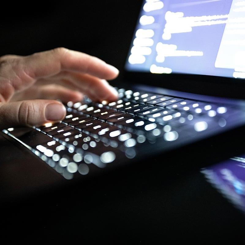 A hand types on a laptop keyboard