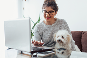 Student working at laptop with dog