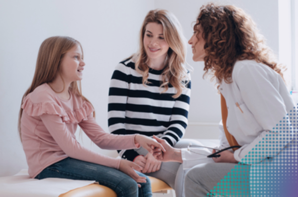 A doctor comforts a teen patient next to her mother.