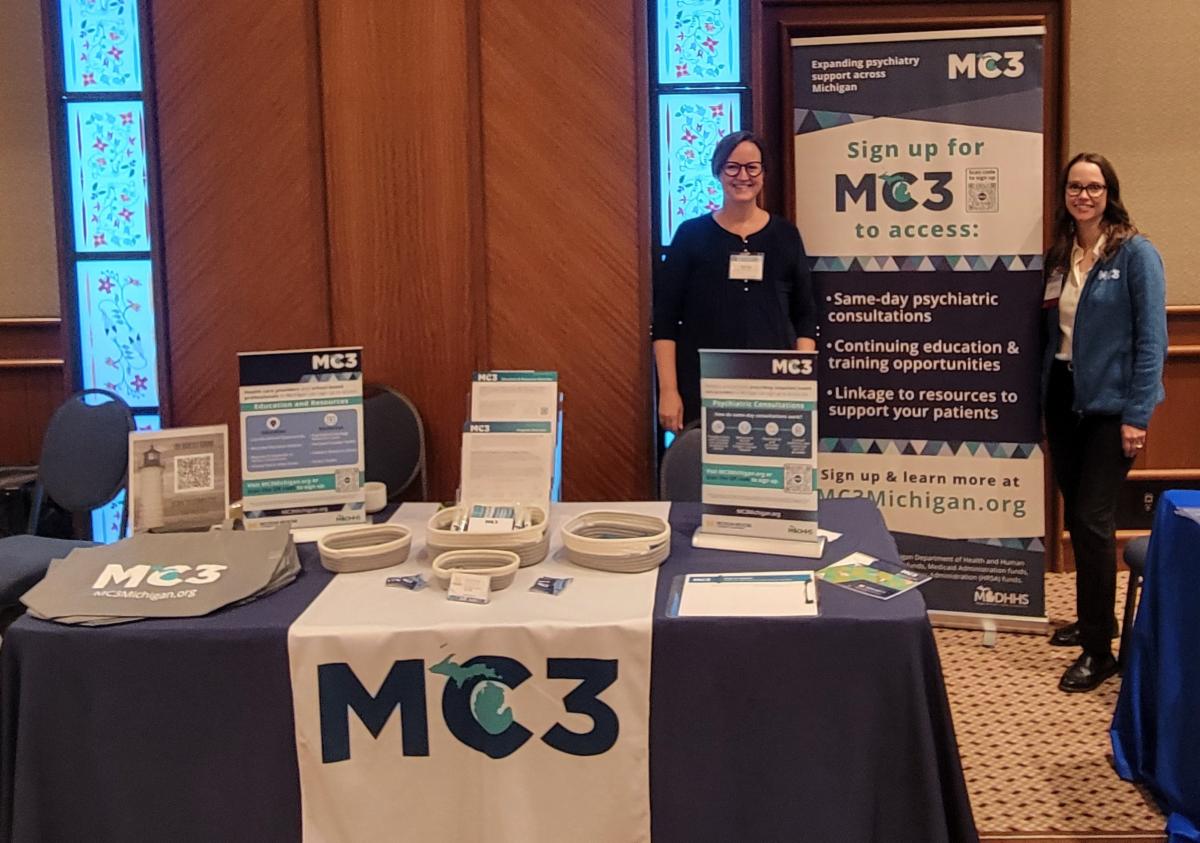 MC3 team members stand behind an exhibit table.