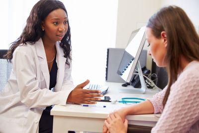 A doctor sits at her desk and speaks to a patient.