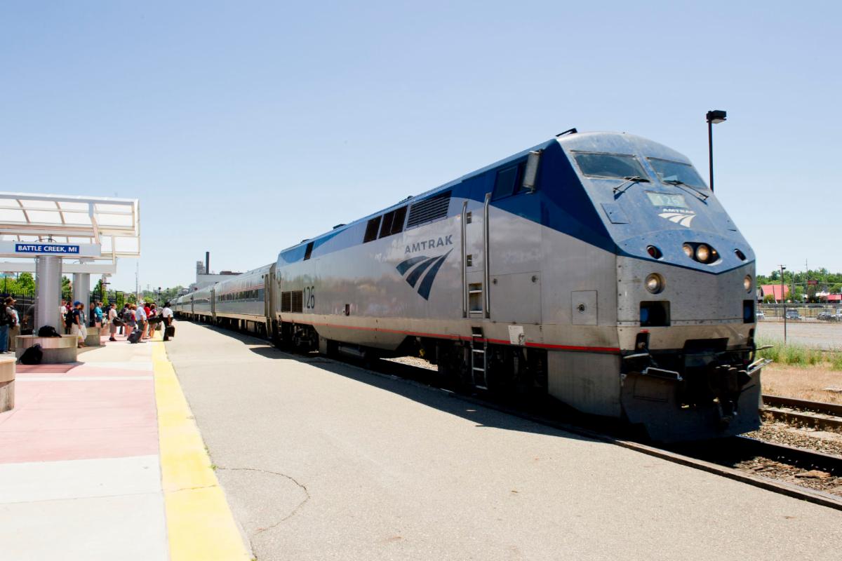 An Amtrak train is stopped at the Battle Creek, Michigan station while passengers wait on the platform to board the train..