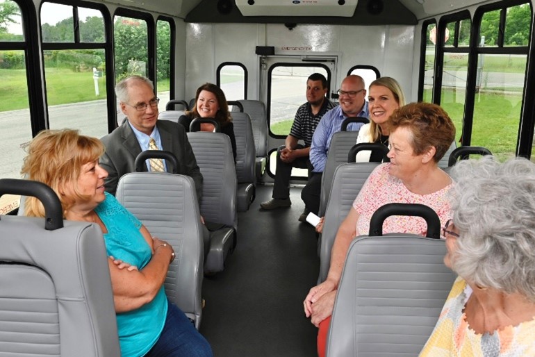 A group of people seated inside a small bus, talking and facing one another during a ride.
