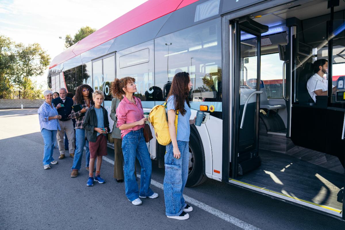 A photo of people waiting in line to get on a bus. 