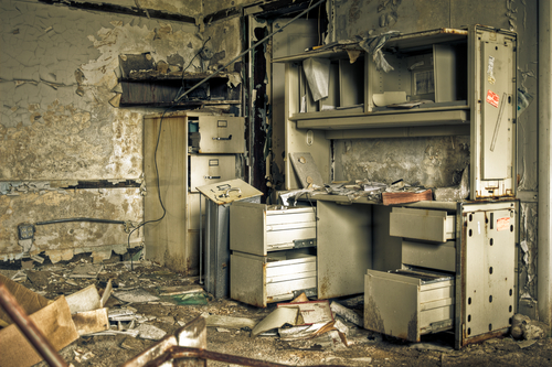 Image of a destroyed office in a derelict abandoned police station surrounded by crumbling walls with peeling paint.