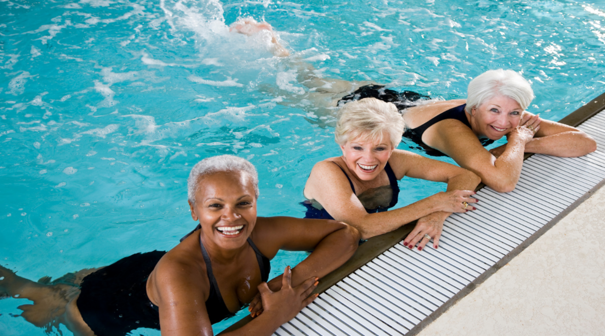 Older Black woman and two older white women in pool, holding onto the side