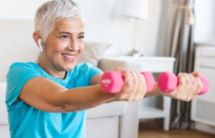 Older woman with gray hair holding up small bright pink weights