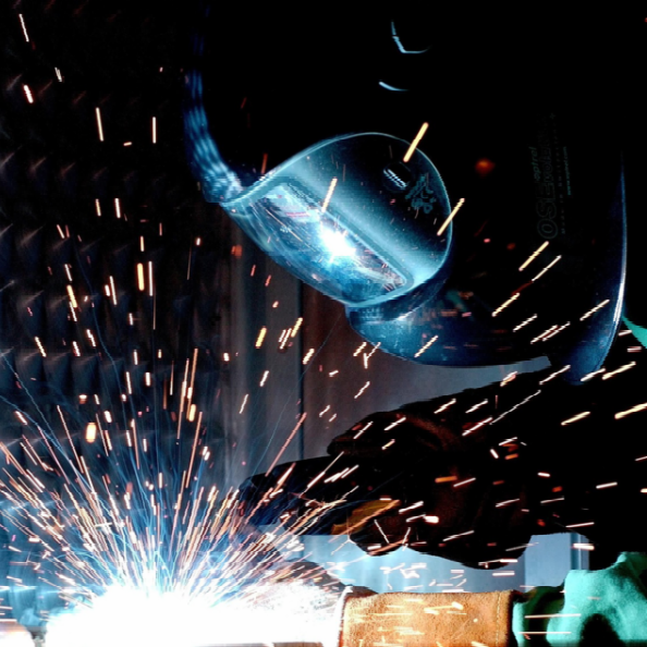 A masked welder with bright, glowing welding sparks