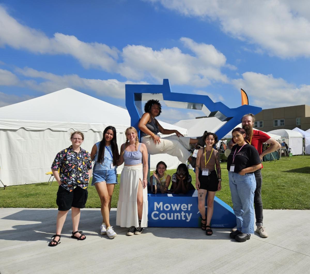 Emerging Artists&nbsp;& Mentor posing for group photo by outline of Minnesota sculpture at the 2024 Austin ArtWorks Festival