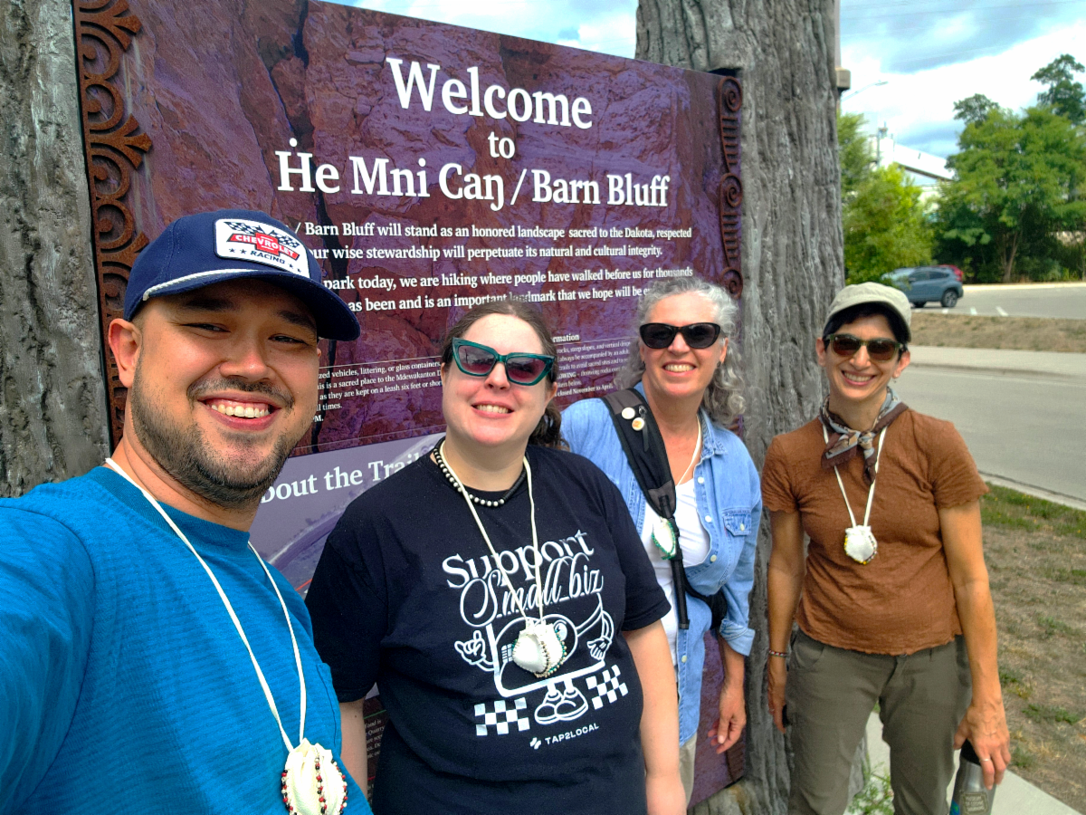 Photo of SEMAC staff standing in front of the sign for He Mni Can bluff.