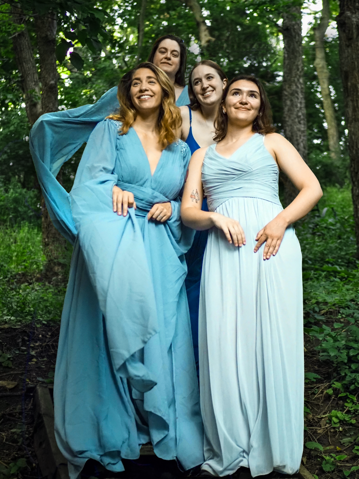 Four Women in blue dresses stand on steps for the play Miller's Daughter, set in the Austrian countryside. 