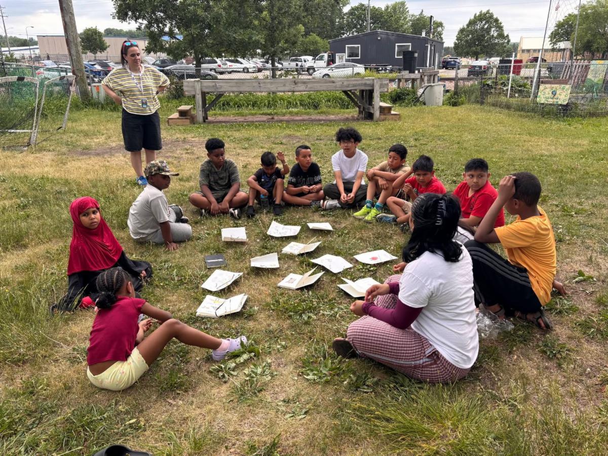 Youth sit outside in a circle during Waves of Alignment