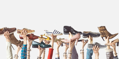 Hands holding different shoes on isolated background