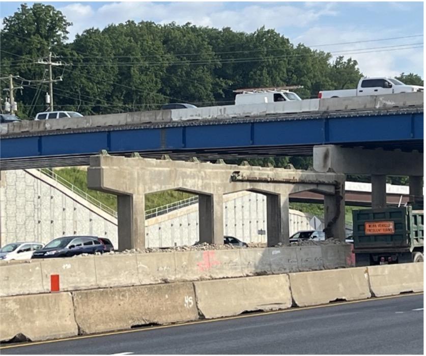 The blue beams of the new Georgetown Pike bridge are visible behind the soon-to-be-demolished center pier of the old bridge located in the median of the Beltway. (June 2025).