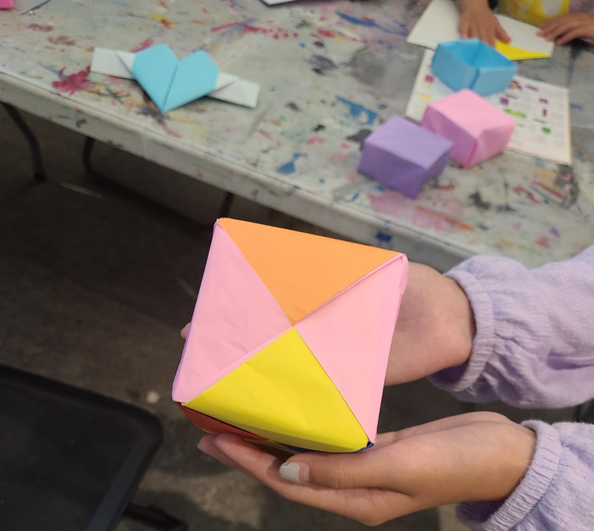Hands holding origami cube