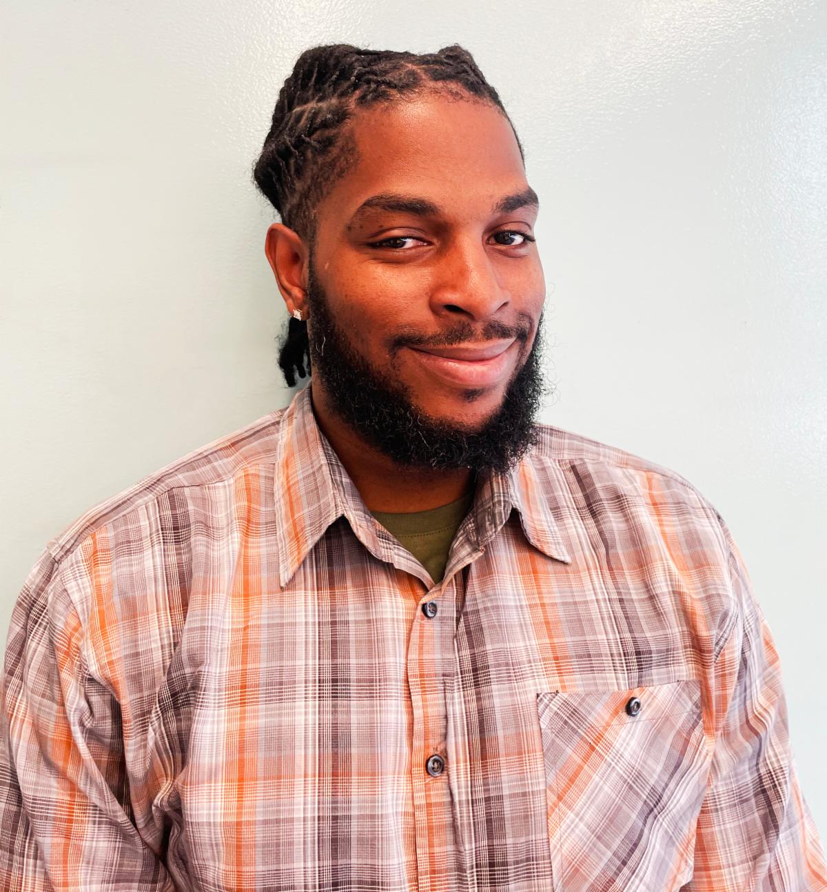 head and shoulders photo of smiling Greg Green wearing a plaid shirt with a collar.